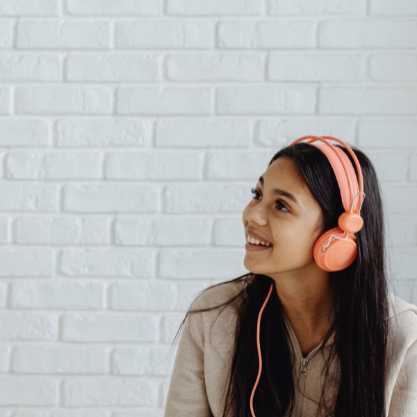 teen girl with orange headphones on and long hair looking off screen