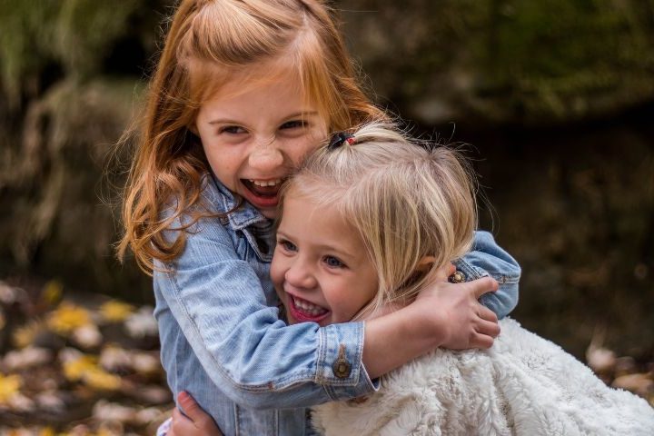 2 young girls hugging and smiling with heads touching