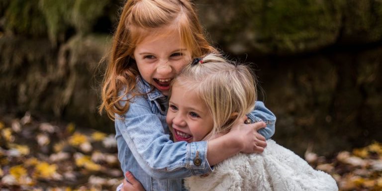 2 young girls hugging and smiling with heads touching