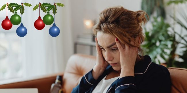lady holding her temples with worried look on her face sat on a sofa with christmas baubles near her head