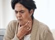 lady holding throat choking whilst sat on sofa