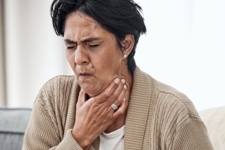 lady holding throat choking whilst sat on sofa