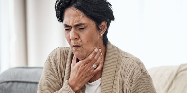 lady holding throat choking whilst sat on sofa