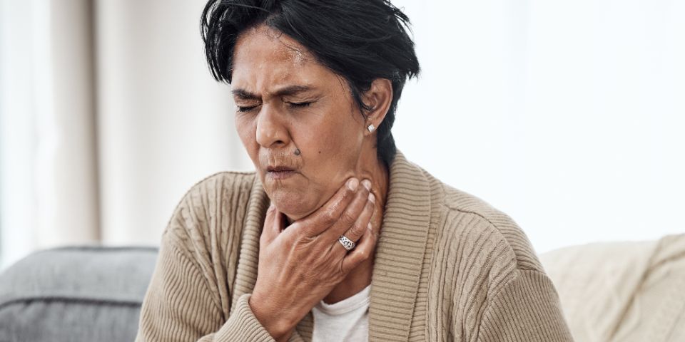 lady holding throat choking whilst sat on sofa